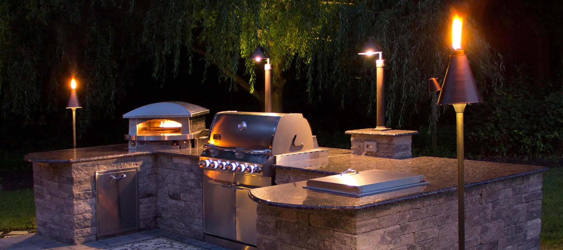 Outdoor kitchen at night with landscape lighting